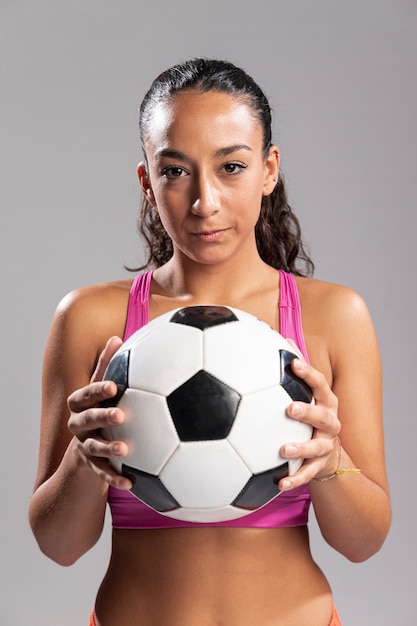 Vista frontal mujer sosteniendo el balón de fútbol