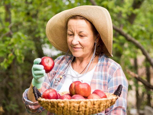 Vista frontal mujer sosteniendo una cesta llena de manzanas