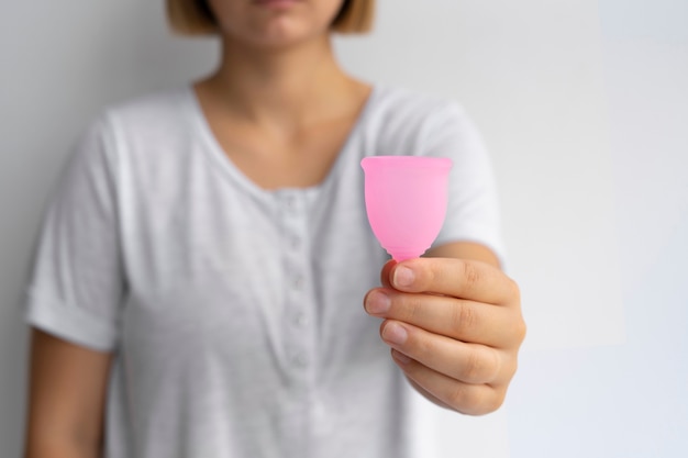 Vista frontal mujer sosteniendo copa menstrual rosa