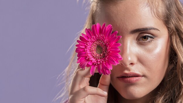 Vista frontal de la mujer sosteniendo una flor cerca de su cara con espacio de copia