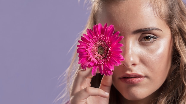 Vista frontal de la mujer sosteniendo una flor cerca de su cara con espacio de copia
