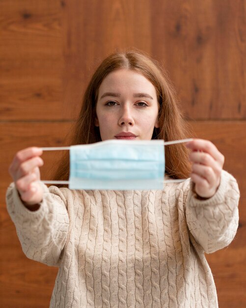 Vista frontal de la mujer sosteniendo una máscara médica