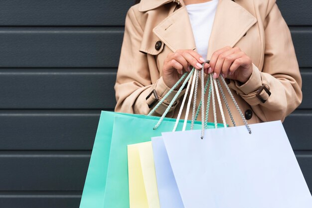 Vista frontal de la mujer sosteniendo un montón de bolsas de la compra.