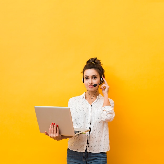 Vista frontal de la mujer sosteniendo portátil listo para atender llamadas en auriculares