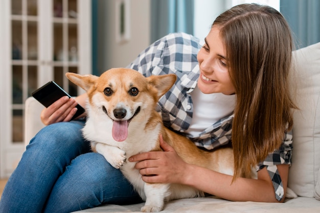 Vista frontal de la mujer con teléfono inteligente y perro