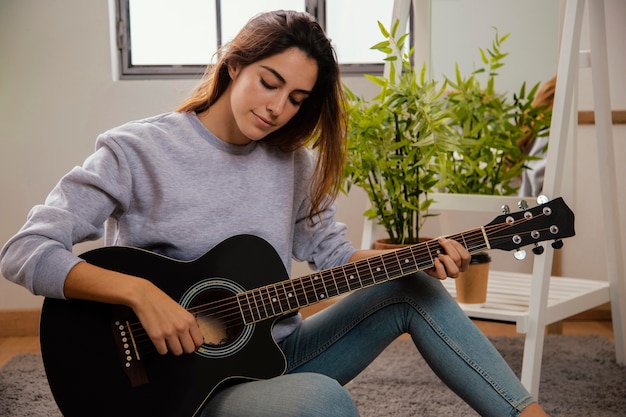 Foto gratuita vista frontal de la mujer tocando la guitarra en casa