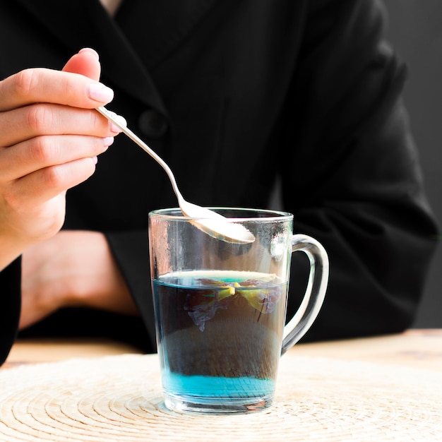 Vista frontal mujer tomando cucharadita de taza de té