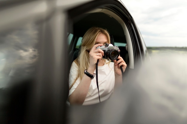 Foto gratuita vista frontal de la mujer tomando fotos con la cámara del coche