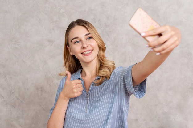 Vista frontal mujer tomando un selfie con su teléfono