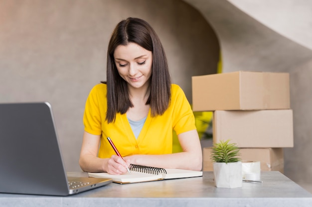 Vista frontal de la mujer en el trabajo escribiendo cosas en el cuaderno