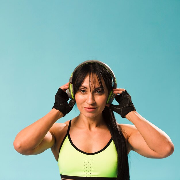 Vista frontal de la mujer en traje de gimnasio posando con auriculares