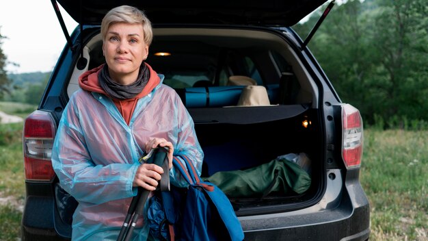 Vista frontal de la mujer turista senior junto al coche