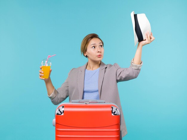 Vista frontal mujer en vacaciones con jugo fresco y su sombrero sobre el fondo azul viaje mar vacaciones viaje viaje