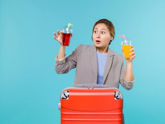 Vista frontal mujer en vacaciones sosteniendo bebidas frescas sobre fondo azul claro viaje por mar viaje en avión de vacaciones viajando