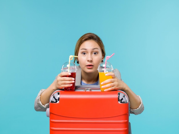 Vista frontal mujer en vacaciones sosteniendo bebidas frescas sobre fondo azul claro viaje viaje vacaciones viaje hidroavión