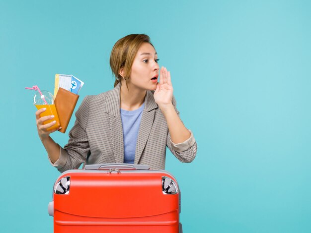 Vista frontal mujer en vacaciones sosteniendo boletos llamando a alguien sobre fondo azul viaje en avión de vacaciones viaje por mar