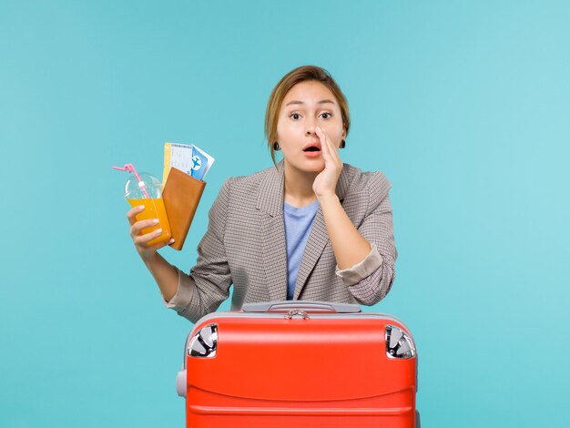 Vista frontal mujer en vacaciones sosteniendo boletos sobre fondo azul viaje en avión de vacaciones viaje por mar