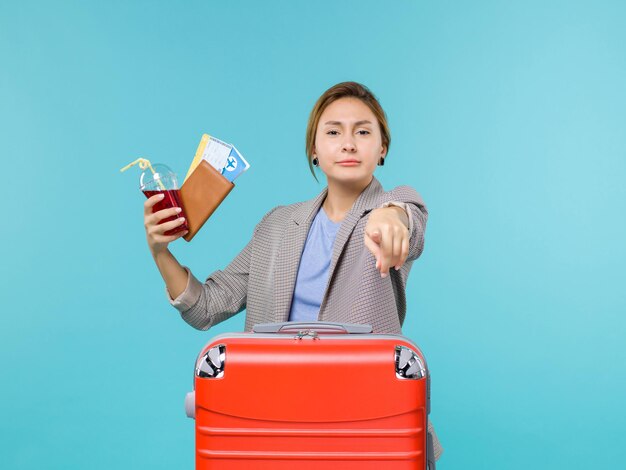 Vista frontal mujer en vacaciones sosteniendo jugo con boletos sobre fondo azul viaje vacaciones viaje viaje hidroavión