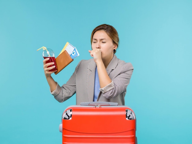 Foto gratuita vista frontal mujer en vacaciones sosteniendo jugo con boletos tosiendo en el fondo azul viaje viaje vacaciones viaje hidroavión