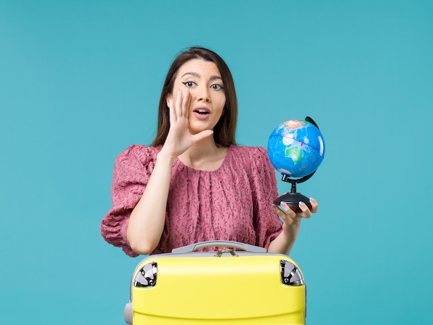 Foto gratuita vista frontal mujer en vacaciones sosteniendo un pequeño globo terráqueo sobre el fondo azul viaje mar mujer viaje vacaciones verano