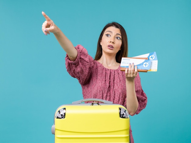 Vista frontal mujer en vacaciones sosteniendo su billetera y boletos apuntando en algún lugar sobre fondo azul viaje mujer verano viaje mar vacaciones