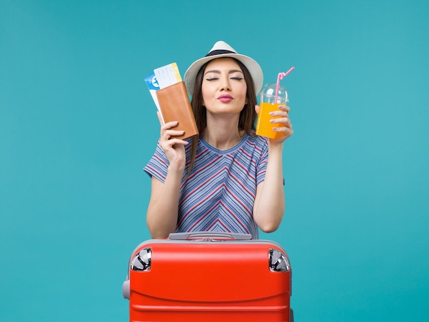 Vista frontal de la mujer de vacaciones sosteniendo su jugo y boletos en el escritorio azul viaje viaje de verano viaje vacaciones mar