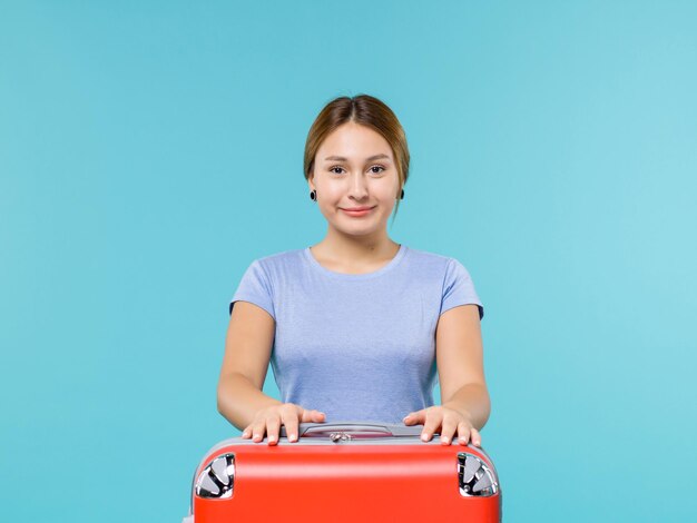 Foto gratuita vista frontal mujer de vacaciones con su bolsa roja sonriendo sobre el fondo azul viaje en avión de vacaciones viaje por mar