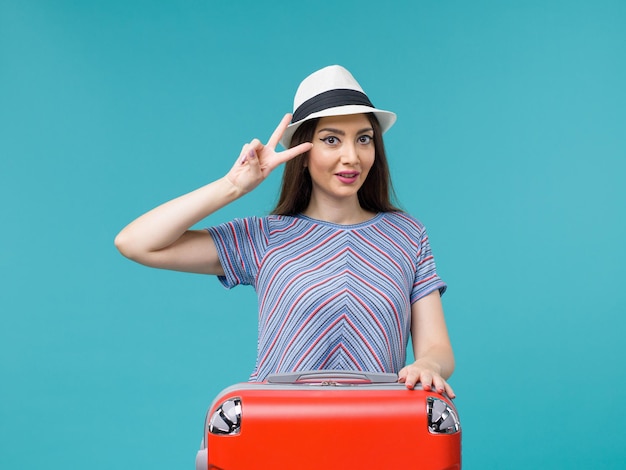 Vista frontal de la mujer de vacaciones con su bolso rojo disfrutando de su viaje en el fondo azul viaje viaje vacaciones viaje femenino