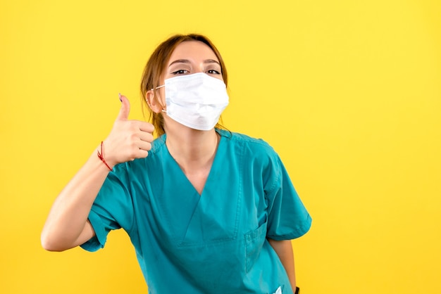 Vista frontal de la mujer veterinaria con máscara en la pared amarilla