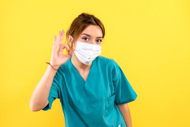 Vista frontal de la mujer veterinaria con máscara en la pared amarilla