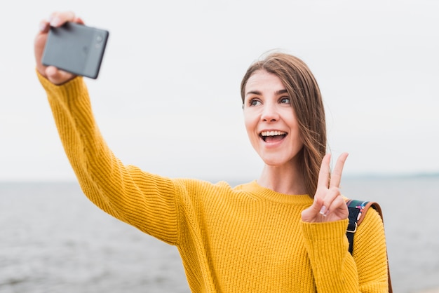 Vista frontal de una mujer viajando sola tomando un selfie