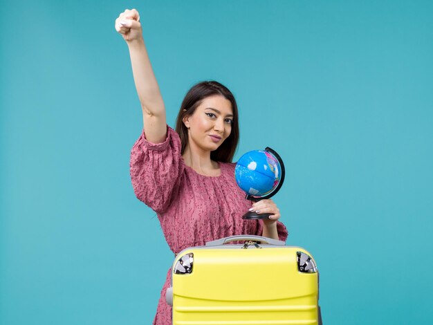 Vista frontal mujer en viaje sosteniendo un pequeño globo sobre fondo azul viaje viaje vacaciones viaje mujer mar