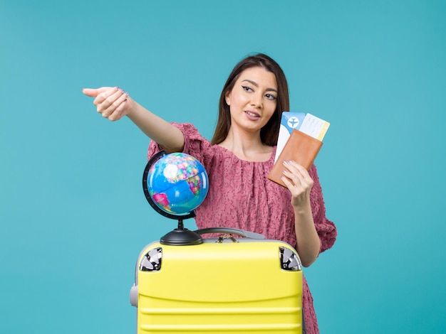 Vista frontal mujer en viaje sosteniendo su boleto sobre fondo azul viaje al mar vacaciones mujer viaje viaje