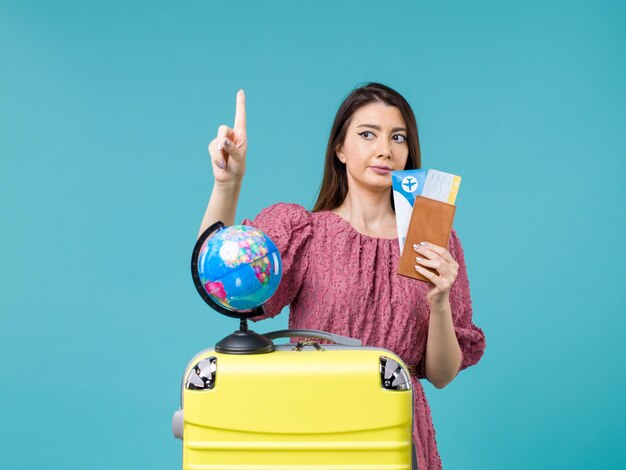 Vista frontal mujer en viaje sosteniendo su boleto sobre fondo azul viaje por mar mujer viaje viaje de vacaciones