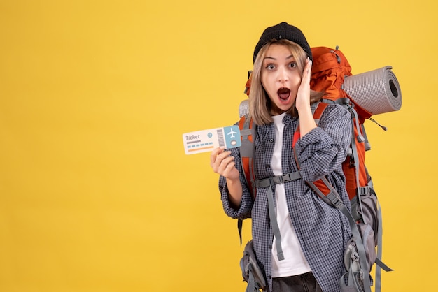 Vista frontal de la mujer viajera asombrada con mochila con boleto