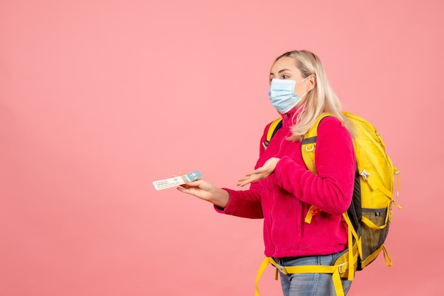 Vista frontal mujer viajero fresco con mochila amarilla con máscara con boleto