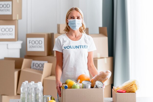 Vista frontal de la mujer voluntaria sosteniendo la caja de donación de alimentos