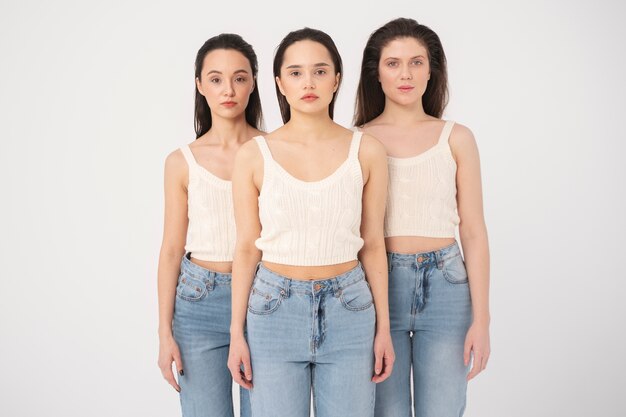 Vista frontal de mujeres en camisetas sin mangas y jeans posando en retratos minimalistas