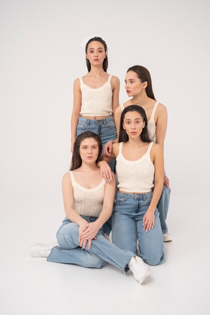 Vista frontal de mujeres en camisetas sin mangas y jeans posando en retratos minimalistas