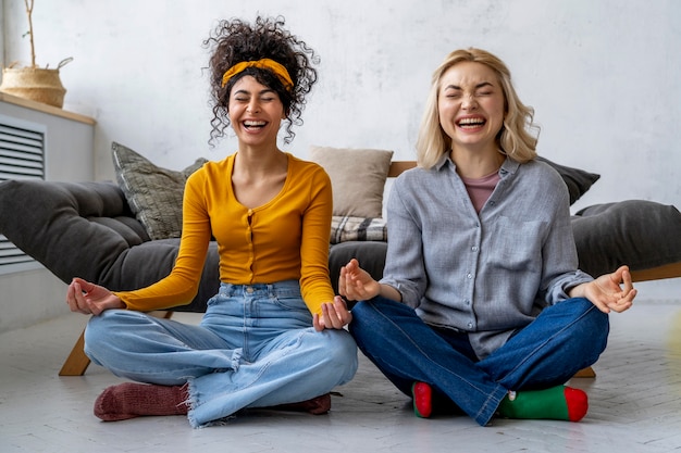 Foto gratuita vista frontal de mujeres felices riendo y haciendo yoga