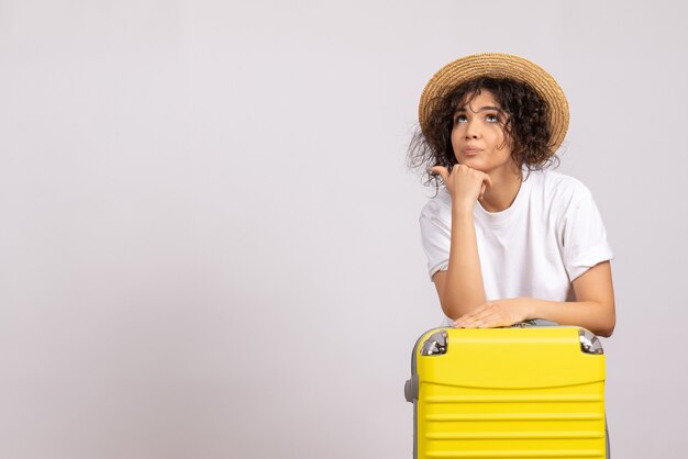 Vista frontal de las mujeres jóvenes con bolsa amarilla preparándose para el viaje sobre fondo blanco, vuelo de color, descanso, viaje, avión, vacaciones turísticas