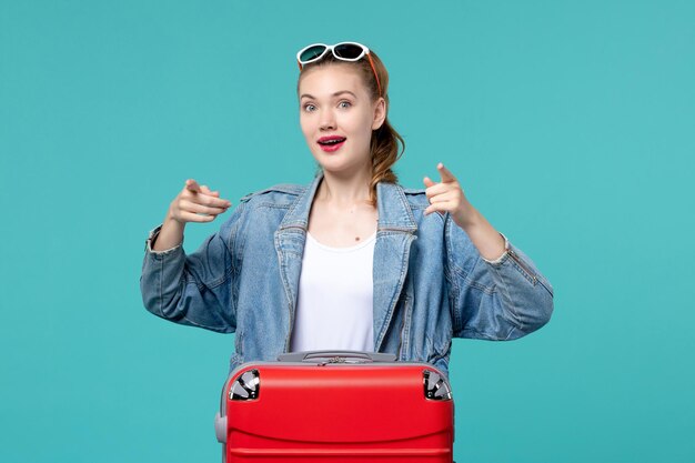 Vista frontal de las mujeres jóvenes con bolsa preparándose para las vacaciones en el espacio azul claro