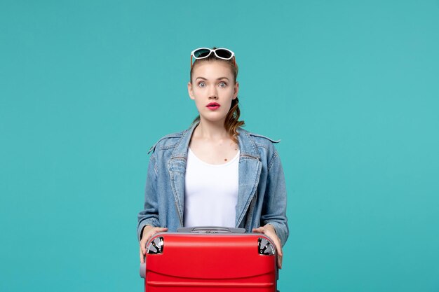 Vista frontal de las mujeres jóvenes con bolsa preparándose para las vacaciones en el espacio azul claro