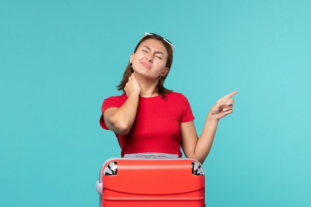 Vista frontal de las mujeres jóvenes con bolsa roja preparándose para las vacaciones con dolor de cuello en el espacio azul