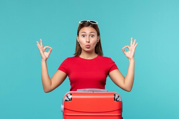 Vista frontal de las mujeres jóvenes con bolsa roja preparándose para las vacaciones en un espacio azul claro