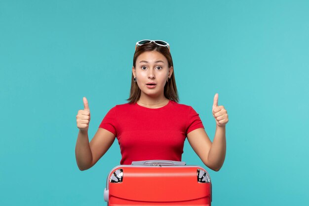 Foto gratuita vista frontal de las mujeres jóvenes con bolsa roja preparándose para las vacaciones en un espacio azul claro