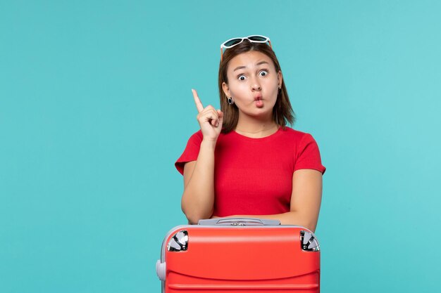 Vista frontal de las mujeres jóvenes con bolsa roja preparándose para las vacaciones en el espacio azul claro