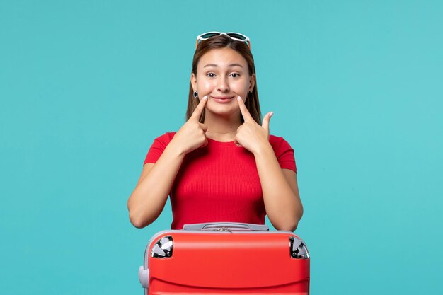 Vista frontal de las mujeres jóvenes con bolsa roja preparándose para las vacaciones en el espacio azul