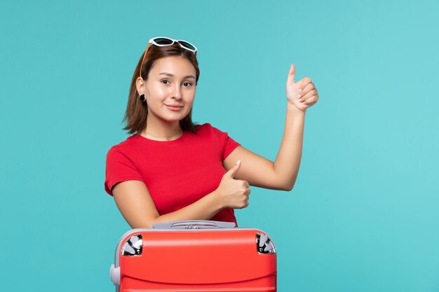 Vista frontal de las mujeres jóvenes con bolsa roja preparándose para las vacaciones con una sonrisa en el espacio azul