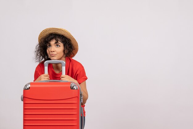 Vista frontal de las mujeres jóvenes con bolsa roja preparándose para el viaje sobre un fondo blanco, viaje de sol, avión, vacaciones turísticas, vuelo de descanso de color